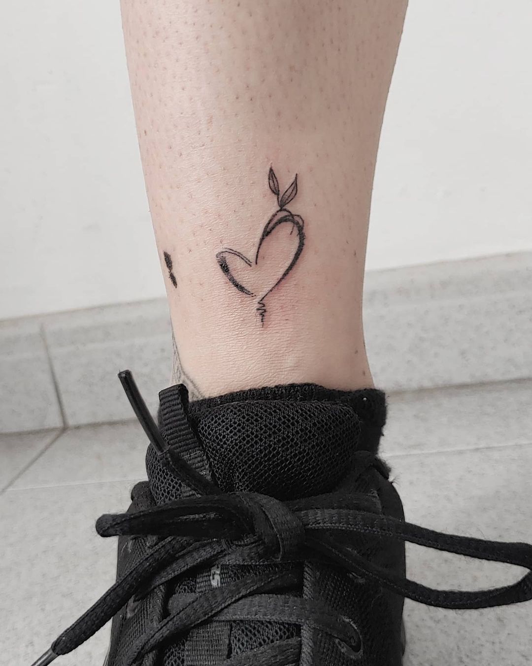 Tiny single needle heart tattoo located on the ankle
